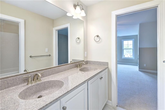 bathroom with baseboards, double vanity, and a sink
