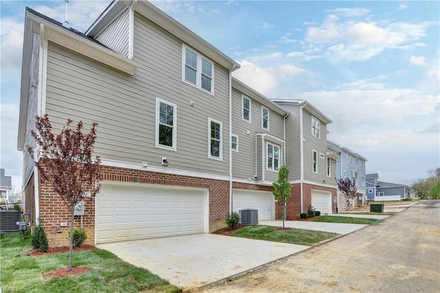 exterior space featuring brick siding, a residential view, driveway, and an attached garage
