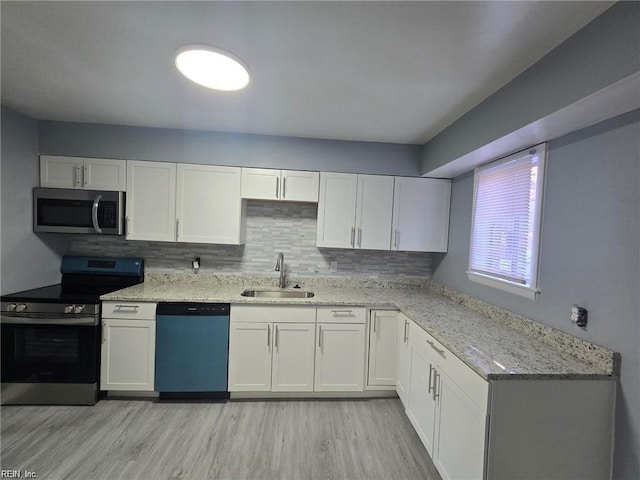 kitchen featuring sink, light hardwood / wood-style flooring, stainless steel appliances, tasteful backsplash, and white cabinets