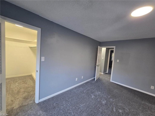 unfurnished bedroom featuring a textured ceiling and dark colored carpet