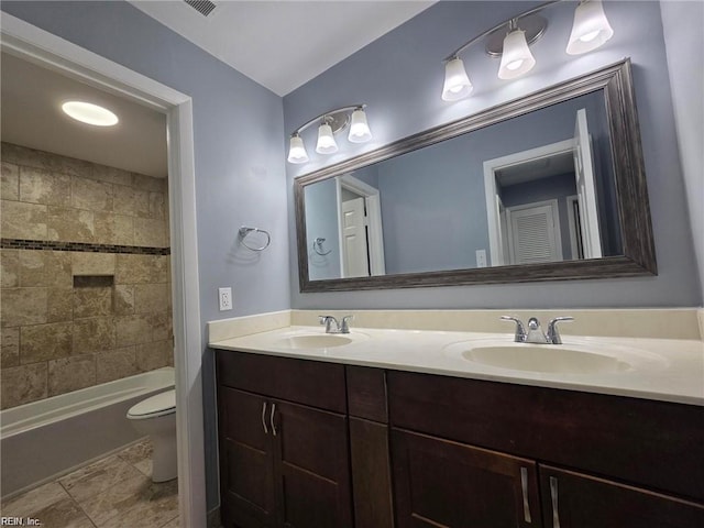 full bathroom featuring tiled shower / bath, vanity, and toilet