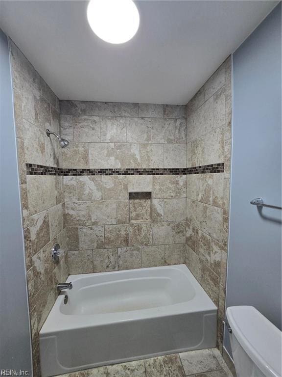 bathroom with toilet and tiled shower / bath