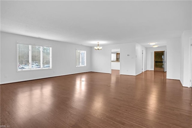 unfurnished living room with dark hardwood / wood-style flooring and a chandelier