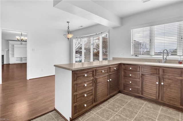 kitchen with sink, light hardwood / wood-style flooring, decorative light fixtures, kitchen peninsula, and a chandelier