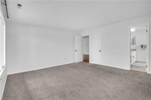 unfurnished bedroom with connected bathroom and carpet floors