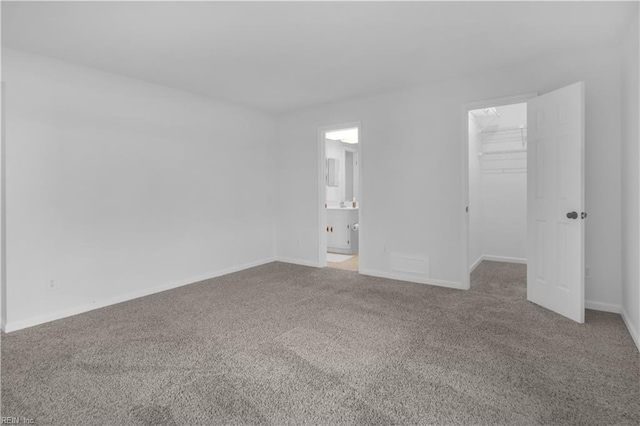 unfurnished bedroom featuring a closet, carpet floors, connected bathroom, and a spacious closet