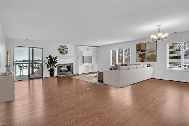 unfurnished living room featuring an inviting chandelier, hardwood / wood-style flooring, and plenty of natural light