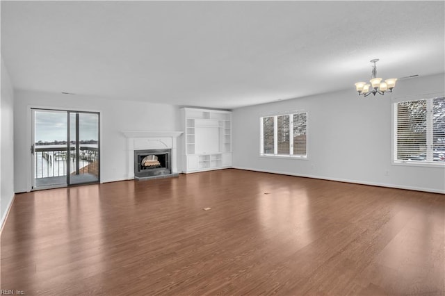 unfurnished living room featuring an inviting chandelier and dark hardwood / wood-style floors