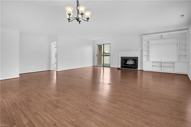 unfurnished living room with dark wood-type flooring, a fireplace, and a notable chandelier