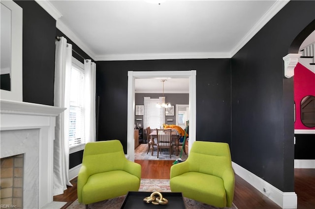 living area featuring a notable chandelier, hardwood / wood-style flooring, a high end fireplace, and ornamental molding