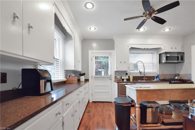 kitchen with white cabinetry, sink, appliances with stainless steel finishes, and hardwood / wood-style flooring