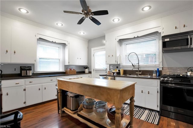 kitchen featuring dark wood-type flooring, white cabinets, crown molding, sink, and gas range oven