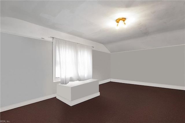 additional living space with vaulted ceiling and dark colored carpet