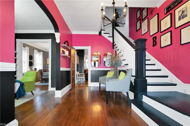 foyer entrance with ornamental molding, an inviting chandelier, and wood-type flooring