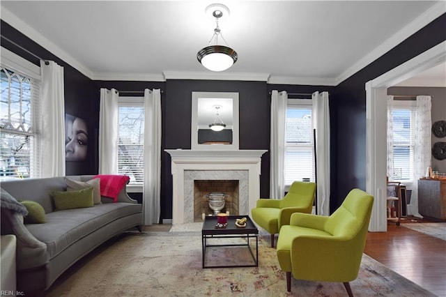 sitting room featuring wood-type flooring, crown molding, a healthy amount of sunlight, and a premium fireplace