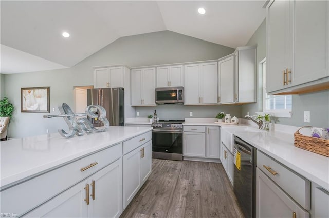 kitchen with stainless steel appliances, white cabinetry, lofted ceiling, and light hardwood / wood-style floors