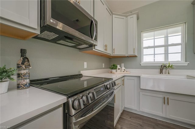 kitchen with appliances with stainless steel finishes, sink, dark wood-type flooring, and white cabinets