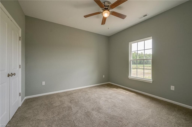 carpeted spare room with ceiling fan