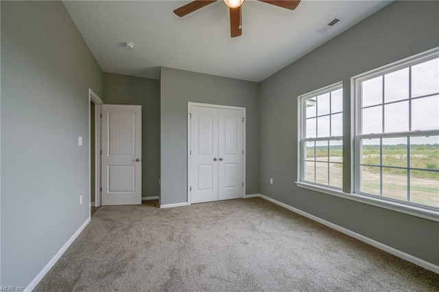 unfurnished bedroom featuring light carpet, a closet, and ceiling fan