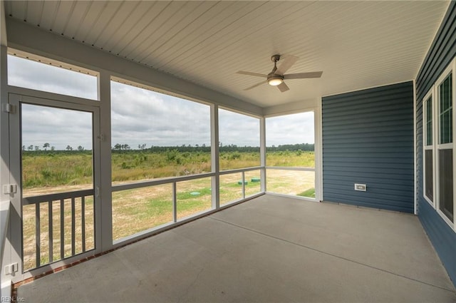 unfurnished sunroom featuring a rural view and ceiling fan