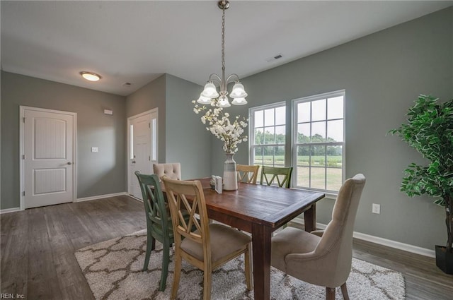 dining room with dark hardwood / wood-style floors and an inviting chandelier