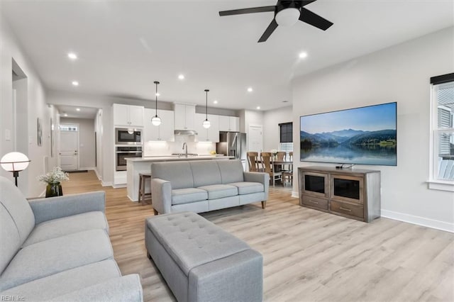 living area featuring light wood finished floors, baseboards, a ceiling fan, and recessed lighting