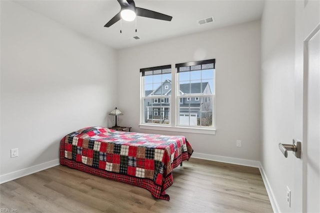 bedroom with a ceiling fan, baseboards, visible vents, and light wood finished floors