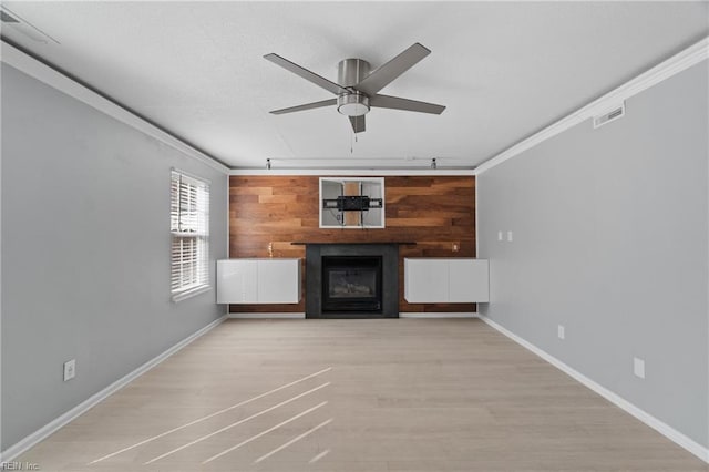 unfurnished living room featuring crown molding, light hardwood / wood-style flooring, ceiling fan, wooden walls, and track lighting