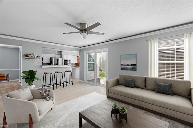 living room featuring crown molding, ceiling fan, and light wood-type flooring