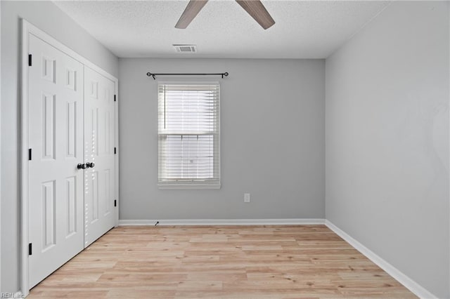 unfurnished room with ceiling fan, light hardwood / wood-style floors, and a textured ceiling