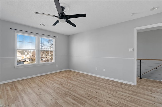 empty room with ceiling fan, light hardwood / wood-style flooring, and a textured ceiling