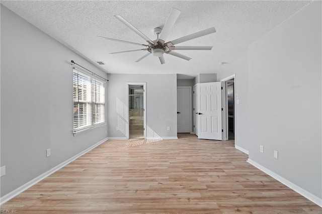 interior space featuring connected bathroom, ceiling fan, a textured ceiling, and light wood-type flooring