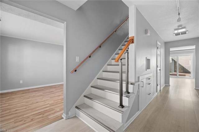 staircase featuring hardwood / wood-style floors and a textured ceiling