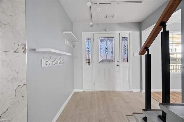 entrance foyer with rail lighting and light hardwood / wood-style floors