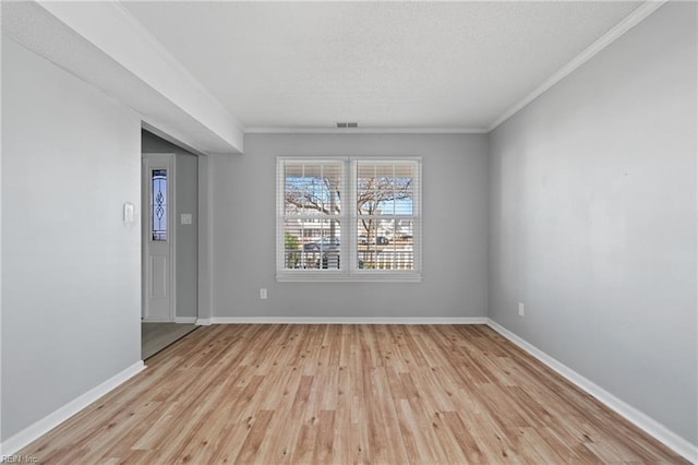 empty room with crown molding and light hardwood / wood-style flooring