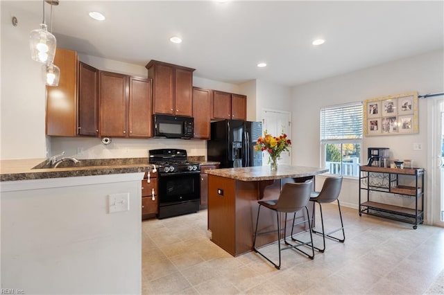 kitchen featuring a kitchen bar, decorative light fixtures, and black appliances