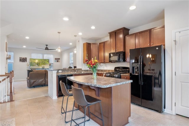 kitchen with a breakfast bar area, hanging light fixtures, a center island, black appliances, and kitchen peninsula