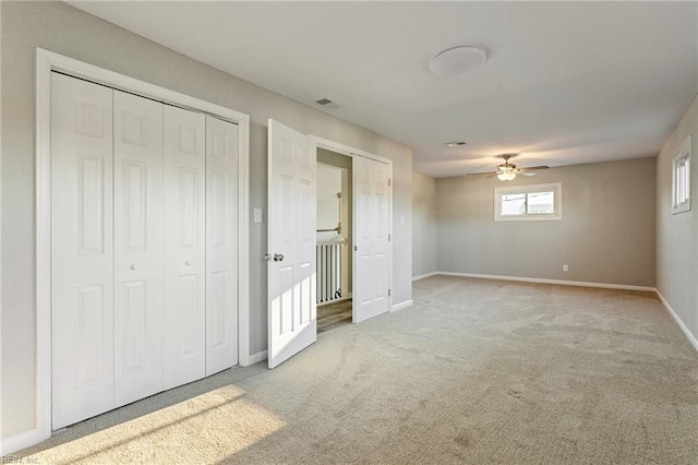 unfurnished bedroom featuring ceiling fan, light colored carpet, and a closet