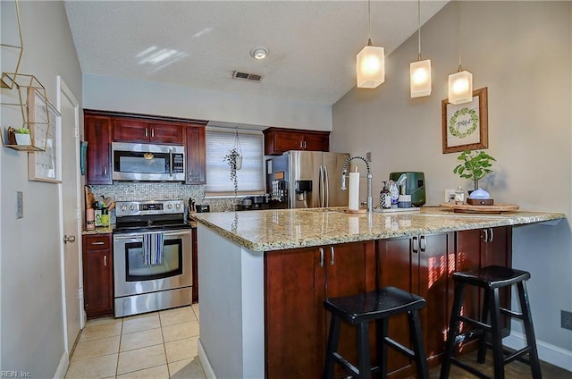 kitchen with tasteful backsplash, a kitchen breakfast bar, kitchen peninsula, pendant lighting, and stainless steel appliances