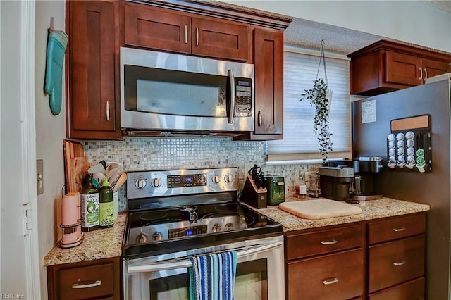 kitchen featuring stainless steel appliances, light stone counters, and decorative backsplash