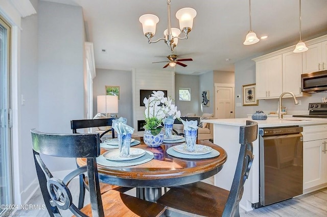 dining room with sink, ceiling fan with notable chandelier, and light wood-type flooring