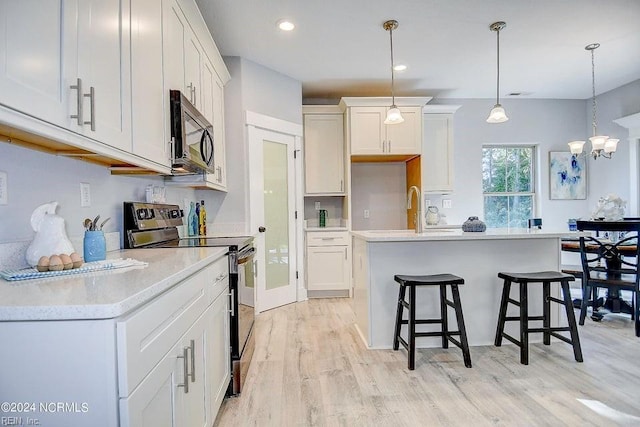 kitchen with white cabinetry, decorative light fixtures, light wood-type flooring, range with electric stovetop, and a kitchen island with sink