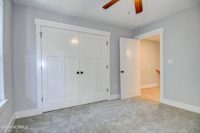 unfurnished bedroom featuring ceiling fan, a closet, and light carpet