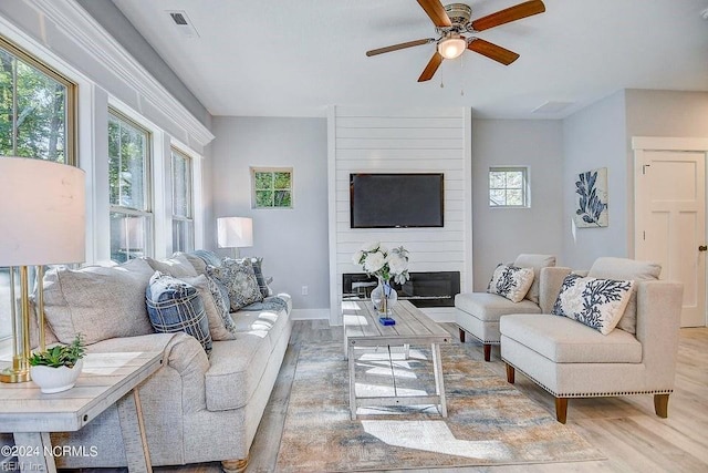 living room featuring a fireplace, light hardwood / wood-style flooring, and ceiling fan