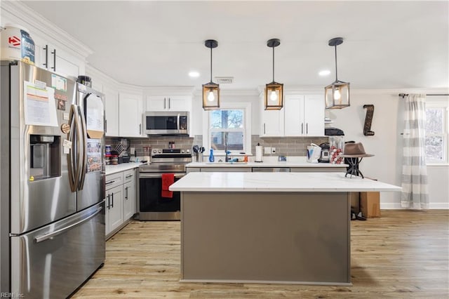 kitchen with pendant lighting, light hardwood / wood-style flooring, appliances with stainless steel finishes, light stone counters, and white cabinets