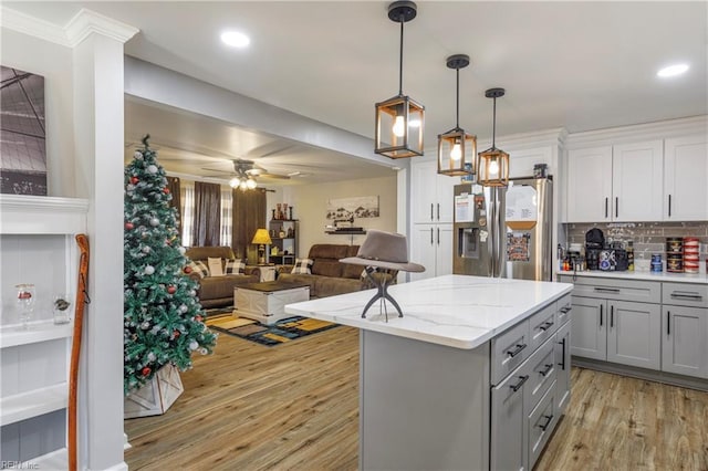 kitchen featuring stainless steel refrigerator with ice dispenser, gray cabinetry, tasteful backsplash, decorative light fixtures, and light hardwood / wood-style floors