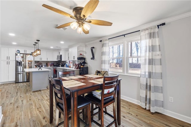 dining space with ornamental molding, light hardwood / wood-style floors, and ceiling fan