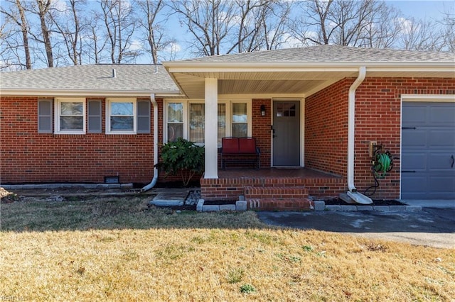 property entrance with a garage, a lawn, and covered porch