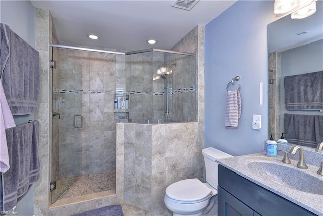 bathroom with a shower with door, vanity, and toilet