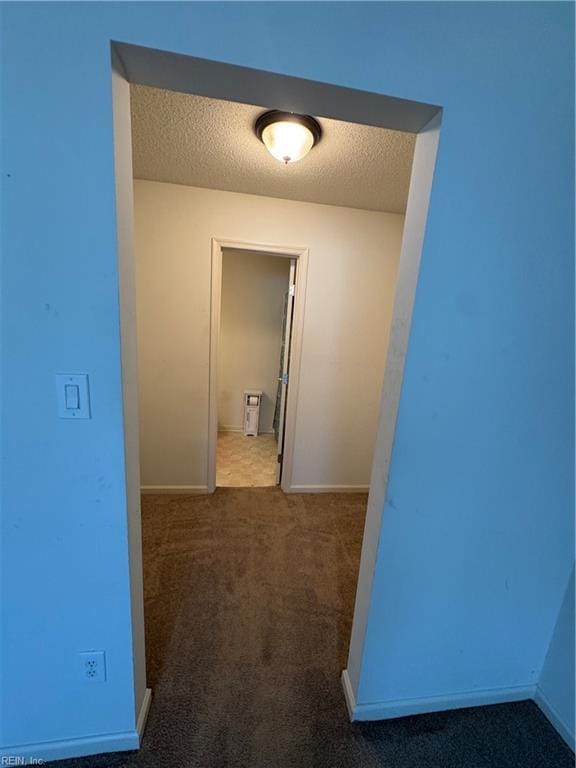 corridor with carpet and a textured ceiling